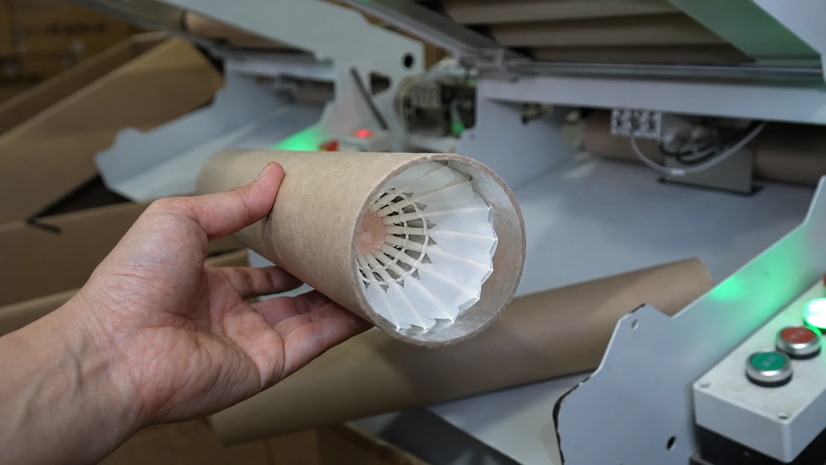 Finished badminton shuttlecock placed inside a cardboard tube at the packaging line